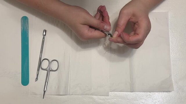 A detailed look at the manicure process: trimming excess cuticles with professional metal nippers against a white background