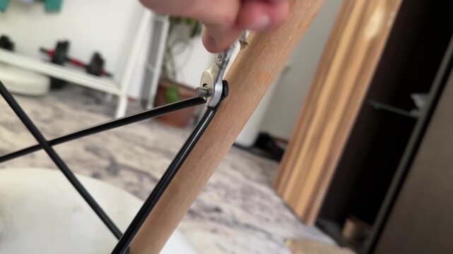 man tightening nut on chair with wrench at home, furniture repair, assembly task, home improvement, everyday work, real people
