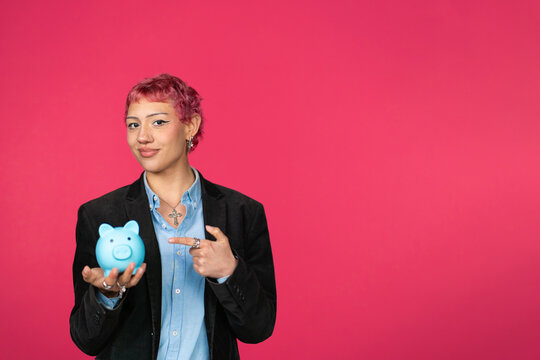 Young person holding blue piggy bank pointing at it