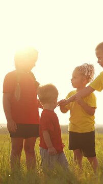Four children play in a sunny field. The girl, wearing a red shirt, interacts with the boy while two other kids in red and yellow observe.