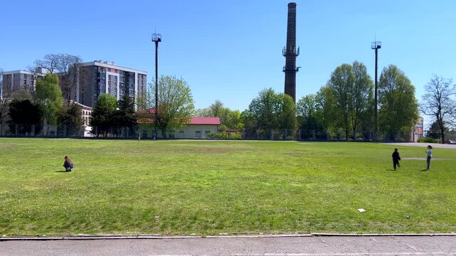 Children playing and throwing frisbee in a sunny city park