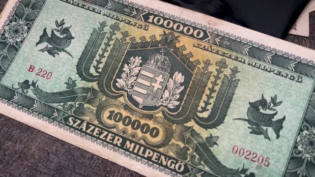 Close up video featuring the reverse design of a vintage Hungarian Szazezer Milpengo banknote. The footage highlights the central heraldic emblem, decorative floral borders, and bird motifs.