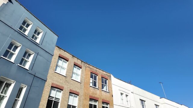 London street showing traditional english brick and modern apartment buildings with a clear blue sky, capturing architectural contrast in the city's residential area