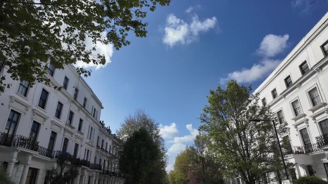 Elegant white victorian terraced houses in a prestigious london neighbourhood on a sunny spring day with blue sky and some clouds, symbolizing luxury living and real estate