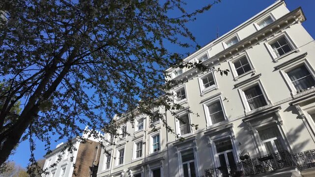 Luxurious classic victorian white terrace townhouses in a typical london neighborhood, featuring elegant sash windows and wrought iron balconies on a sunny day
