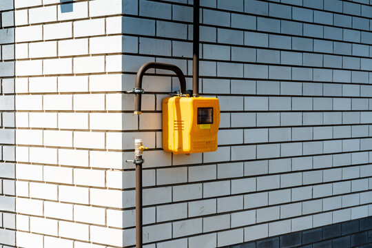Outdoor Gas Supply Meter With Digital Display And Safety Features. Installation Of Yellow Gas Meter On Brick Wall Featuring Digital Readout And Safety Indications For Maintenance
