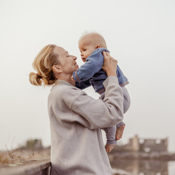 Tender woman caressing her little baby boy infant child outdoors on autumn trip to Secovlje salinas landscape park, Slovenia. Mother's unconditional love for her child