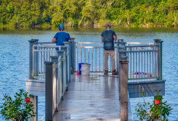 Obraz premium Two men fishing from a dock on a lake