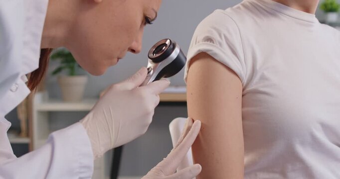 Medical consultation, doctor wearing gloves and lab coat, closely examining patient arm skin mole, using dermatoscope, performing dermatological check up, health monitoring providing skin cancer care