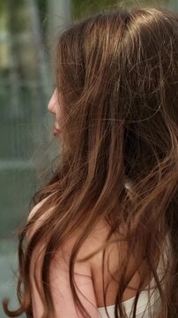 Young woman spins in a dance and briefly glances back at the camera, gentle smile and flowing hair creating a light flirty mood and sense of freedom.