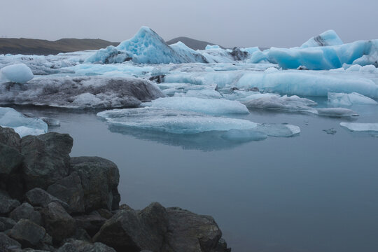 Blue icebergs floating in a misty glacial lagoon