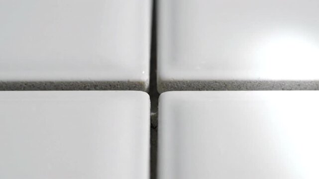White ceramic tile close up showing grout lines and smooth surface with slight texture, creating clean and minimalistic pattern in neutral setting