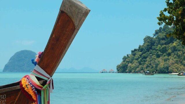 Traditional long-tail boat prow decorated with colorful ribbons, tropical beach in Southern Thailand, summer vacation travel background