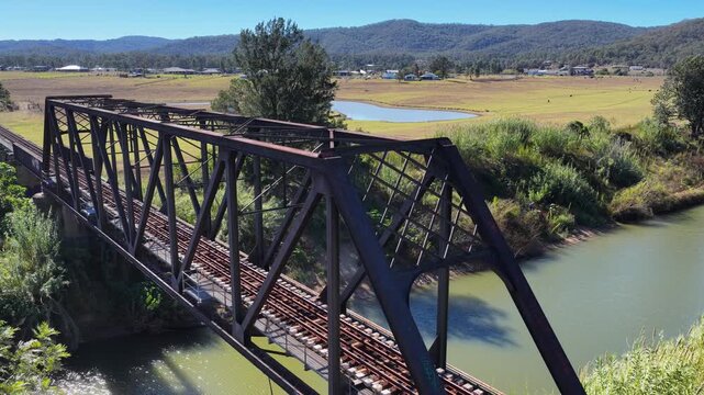 Aerial ascending video of the Paterson rail bridge crossing the Hunter River in New South Wales Australia. Drone footage rises above the historic railway bridge