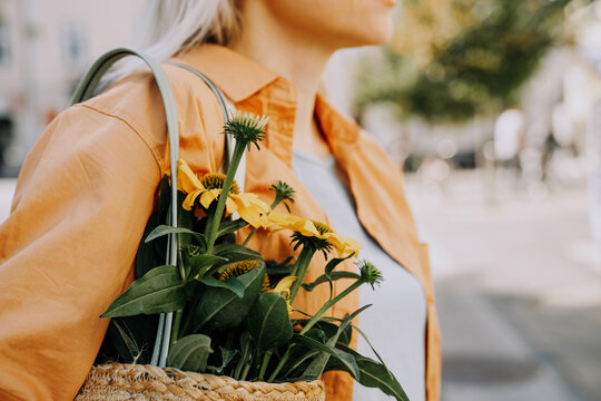Beautiful young woman buying fresh flowers at city center market. Flower and food local market. Concept shopping, small business, sustainable production.
