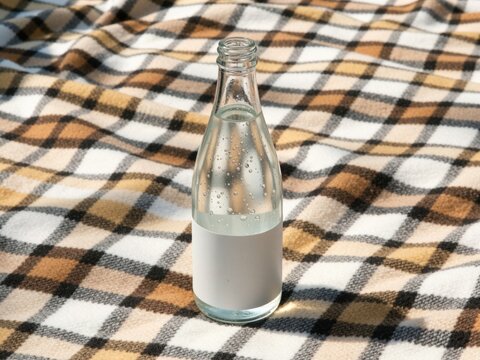 Glass bottle of sparkling water on picnic blanket