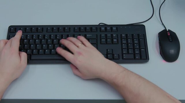A person is typing on a keyboard with a mouse in front of them. Concept of productivity and focus, as the person is engaged in a task that requires their full attention