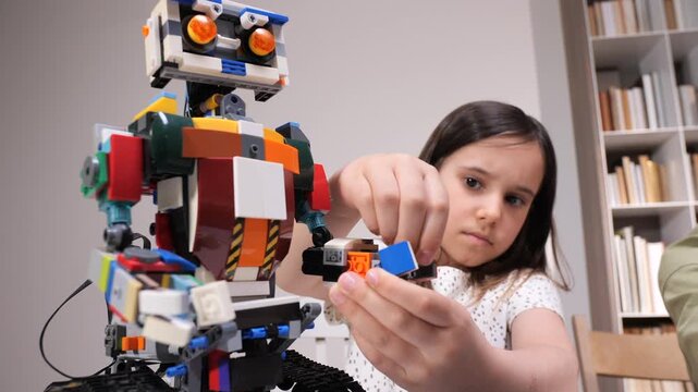 Young girl constructing a colorful robot from building blocks, focusing intensely on connecting components, actively engaging in stem education and creative play indoors