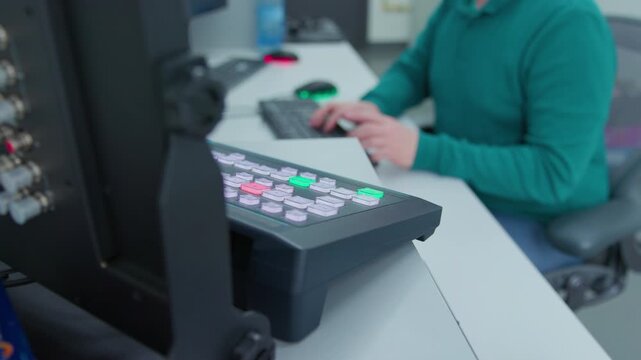An engineer doing his job in a control room. He sits at a keyboard and control panel on a desk