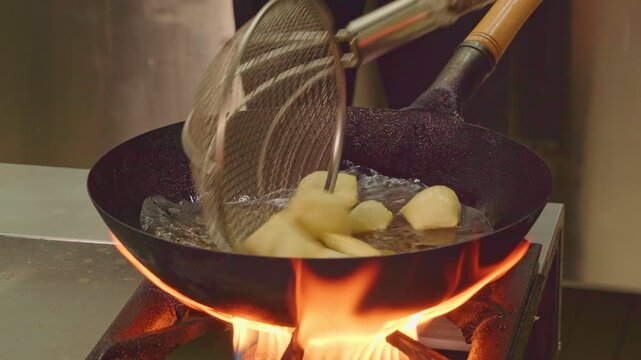 Traditional cuisine of ancient nomads. Festive dish for Nauryz.
Person stirring baursaks in cast iron cauldron with slotted spoon. The national bread of the Kyrgyz, Tajiks, Uzbeks