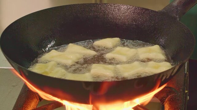 Traditional cuisine of ancient nomads. Festive dish for Nauryz.
Person stirring baursaks in cast iron cauldron with slotted spoon. The national bread of the Kyrgyz, Tajiks, Uzbeks 