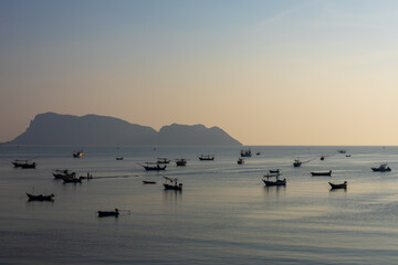 Naklejka premium Peaceful seascape sunset silhouette mountain small fishing boat floating calm ocean water peaceful tranquility relax outdoor recreation marine nature scenery