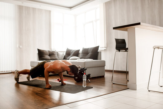 Young man go in for sport at home. Full size picture of t-shirtless guy sportsman stand in plank position alone in room. Male model try to do his best and exercise. Hardworking real person