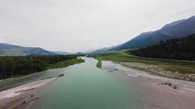 Fast-paced FPV drone cinematic flight over a rapid turquoise mountain river towards a man standing on a scenic cliff. Filmed in Altai Mountains, East Kazakhstan. Lush green summer landscape with majes