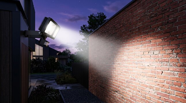 Modern sleek matte black LED motion sensor floodlight casting a brilliant white beam across a textured red brick wall during deep purple.