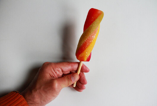 Helado polo de palo sabor fruta y hielo de colores pirulo en mano icre cream en calor hot de verano summer para refrescar y fondo blanco