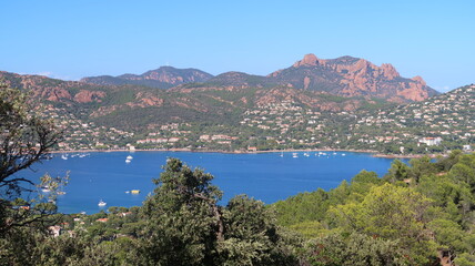 Fototapeta premium Panorama sur la rade d’Agay (Saint-Raphaël / Var), la mer Méditerranée et le massif de l’Estérel : vue, depuis le Dramont, sur une partie du Rastel, le pic du Cap Roux et le pic de l’Ours (France)