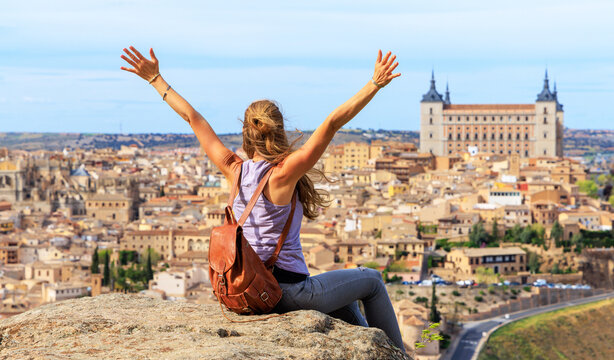 happy woman traveler with arms outstretched enjoying the panoramic view of Toledo, Spain