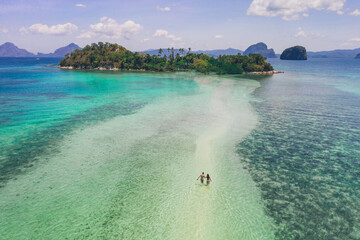Naklejka premium Enjoying the time at the beach. People walking on the white sand, with tropical jungle in the background. Concept about traveling and nature