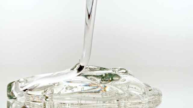 Macro shot of Clear Cosmetic Gel, Fluid, Serum Pours from Above on a White Glass Surface. Closeup Organic Products, Medicine. Dermatology Science Laboratory. High quality 4k footage