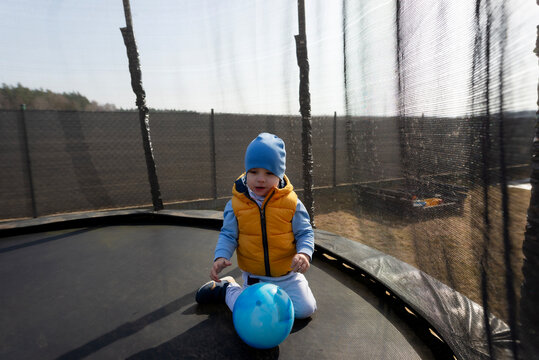 Toddler boy playing with blue ball on trampoline