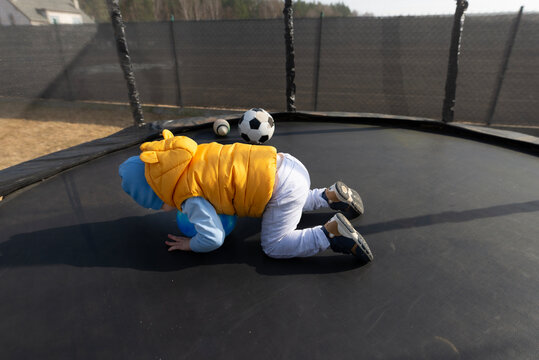 Toddler boy playing with ball on outdoor trampoline