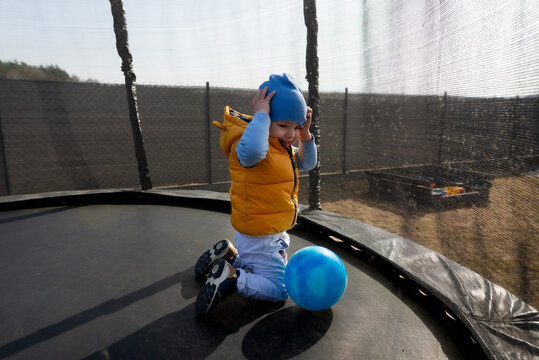 Toddler boy playing with a blue ball on a trampoline