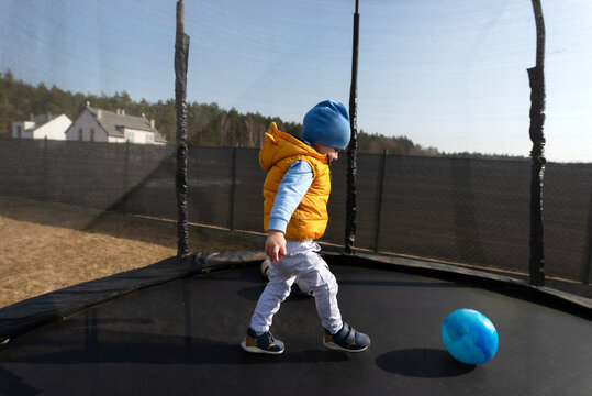Toddler boy playing with ball on trampoline outdoors