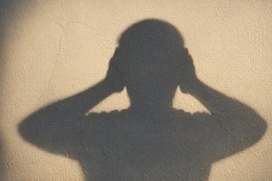 A person shielding their identity by covering their face with their hands