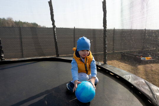 Toddler boy playing with ball on trampoline outdoors