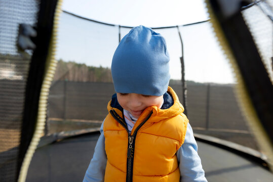 Toddler boy playing outdoors on trampoline smiling