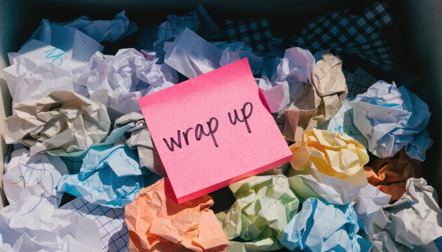 Wrap up note on pink sticky paper with crumpled colorful paper balls in background, symbolizing completion and finalizing tasks
