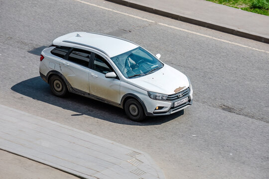 white Lada Vesta SW Cross car driving on an asphalt road. The vehicle is captured from a slightly elevated angle