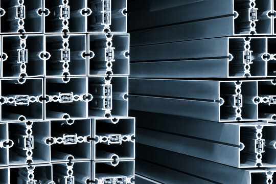 Aluminum profiles form precise rectangular grids. Each section connects with circular fasteners. Smooth metallic surfaces reflect light softly. Stacked arrangements show organized structure