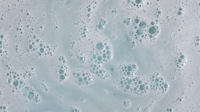 Bubbles of white soap foam on a blue background. Bathtup Soap Foam. Texture of Soap Foam Bubbles. Natural White Shampoo Bubbles Motion. . High quality 4k footage