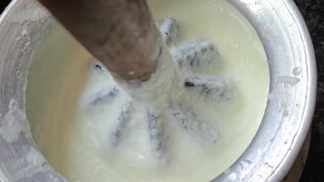 A wooden Madhani rhythmically spins in curd, expertly separating fresh butter from tangy buttermilk. This sacred Bilona craft then transforms that cream into pure ghee, the golden essence of health.