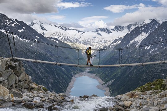 Hiker, woman on suspension bridge at the Olpererh&uuml;tte, Schlegeis reservoir, Schlegeis reservoir, Zillertal Alps, Schlegeiskees glacier, Zillertal, Tyrol, Austria