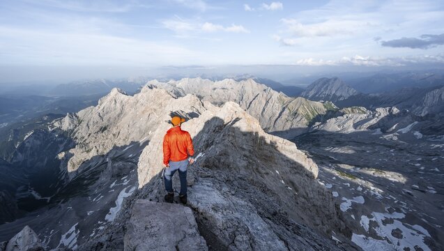 Mountaineer on a narrow rocky steep ridge, view of the H&ouml;llental and the Alpspitze from the Jubil&auml;umsgrat, in the evening light Zugspitze, Wetterstein range, Bavaria, Germany