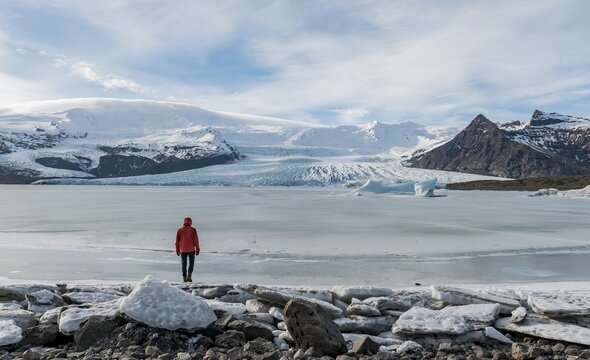 Man stands at Frozen Lagoon with ice floe, mountains, Fjalls&aacute;rl&oacute;n Glacier Lagoon, South Iceland, Iceland