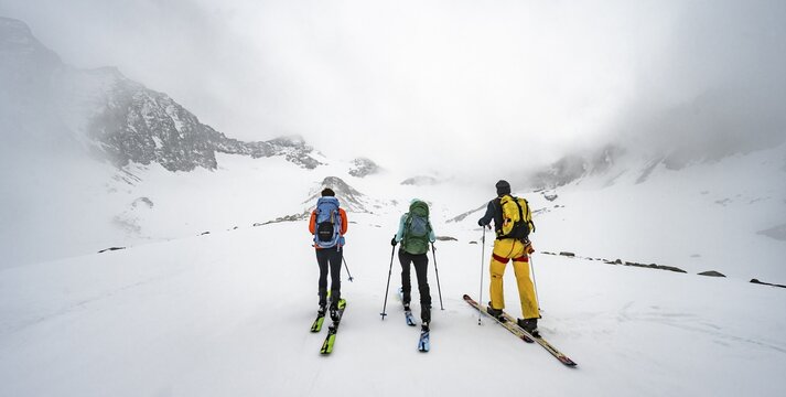 Three ski tourers climbing Sommerwandferner, cloudy mountains, Stubai Alps, Tyrol, Austria